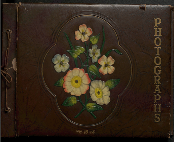 Brown leather photo album with embossed colorful flowers and gold “PHOTOGRAPHS” and "EBS" text on the cover.